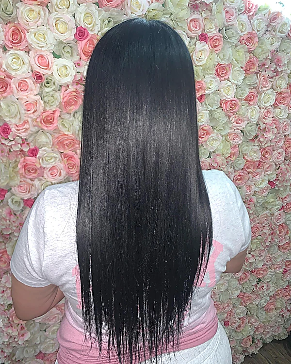 El mismo cabello largo, lacio y brillante después del tratamiento, frente al muro de rosas