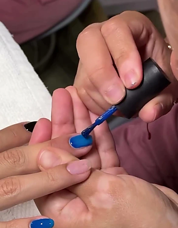 Manicurista aplicando esmalte azul rey