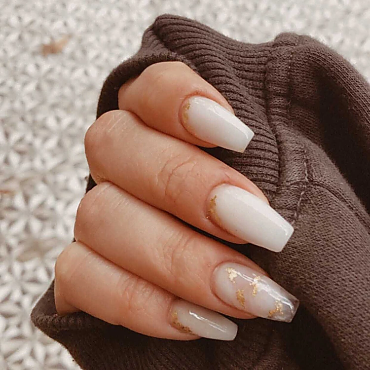 Uñas largas tipo coffin en tono nude lechoso con detalles de hoja dorada